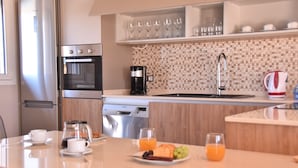 Een moderne keuken met een inbouwoven, koffiezetapparaat en een eethoek met ontbijtartikelen.