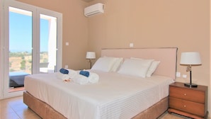 Een slaapkamer met een groot bed, twee bedlampen, een nachtkastje en een glazen schuifdeur die leidt naar een buitenruimte.