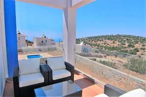 A balcony with a glass railing, a wicker sofa, and a small table.