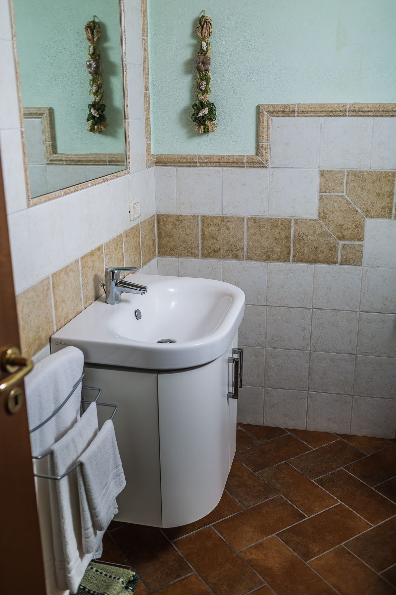 Une salle de bain avec un lavabo blanc, un porte-serviettes et des miroirs décoratifs au mur.