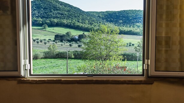 Ein Zimmer mit Fensterblick auf eine grüne Landschaft mit Hügeln.