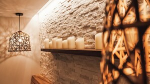 Een gezellig interieur met een stenen muur, een houten bank en een hanglamp.