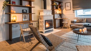 Een gezellige woonkamer met een open haard, houten meubels en boekenplanken met boeken en decoratieve objecten.