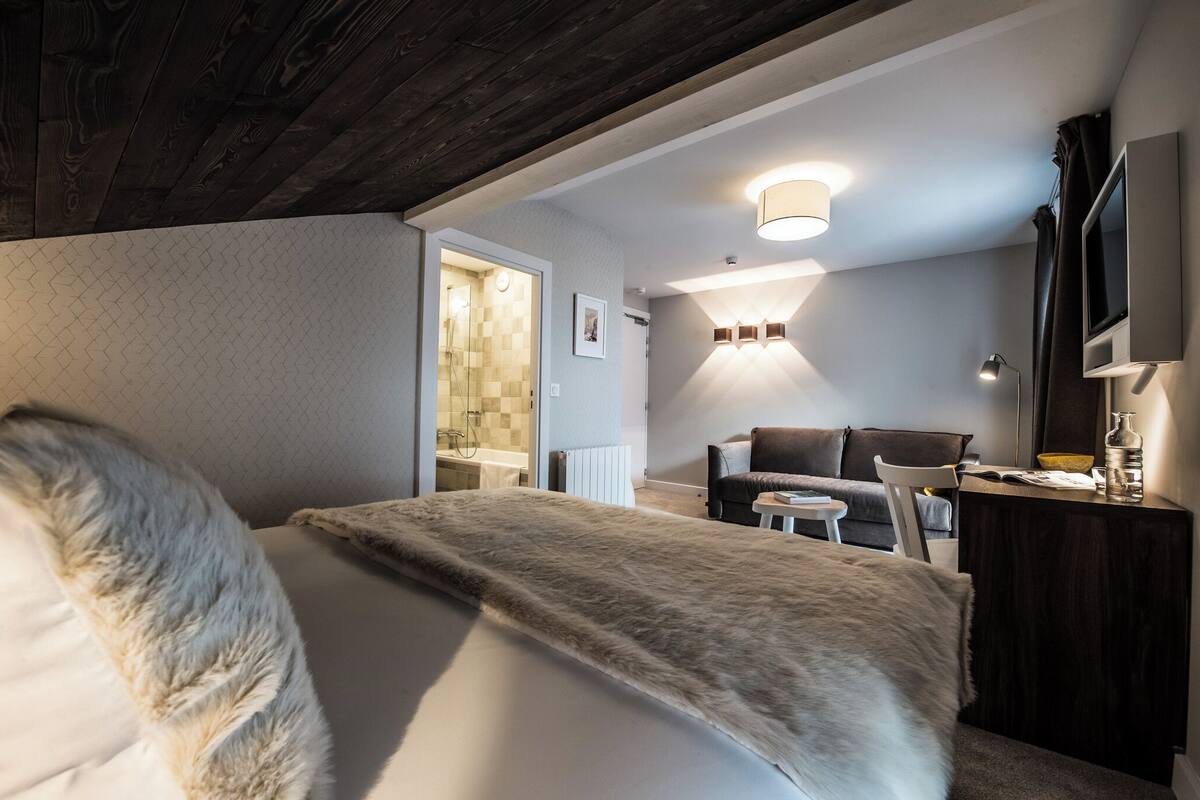 Une chambre moderne avec un grand lit, un canapé, un bureau et une télévision.