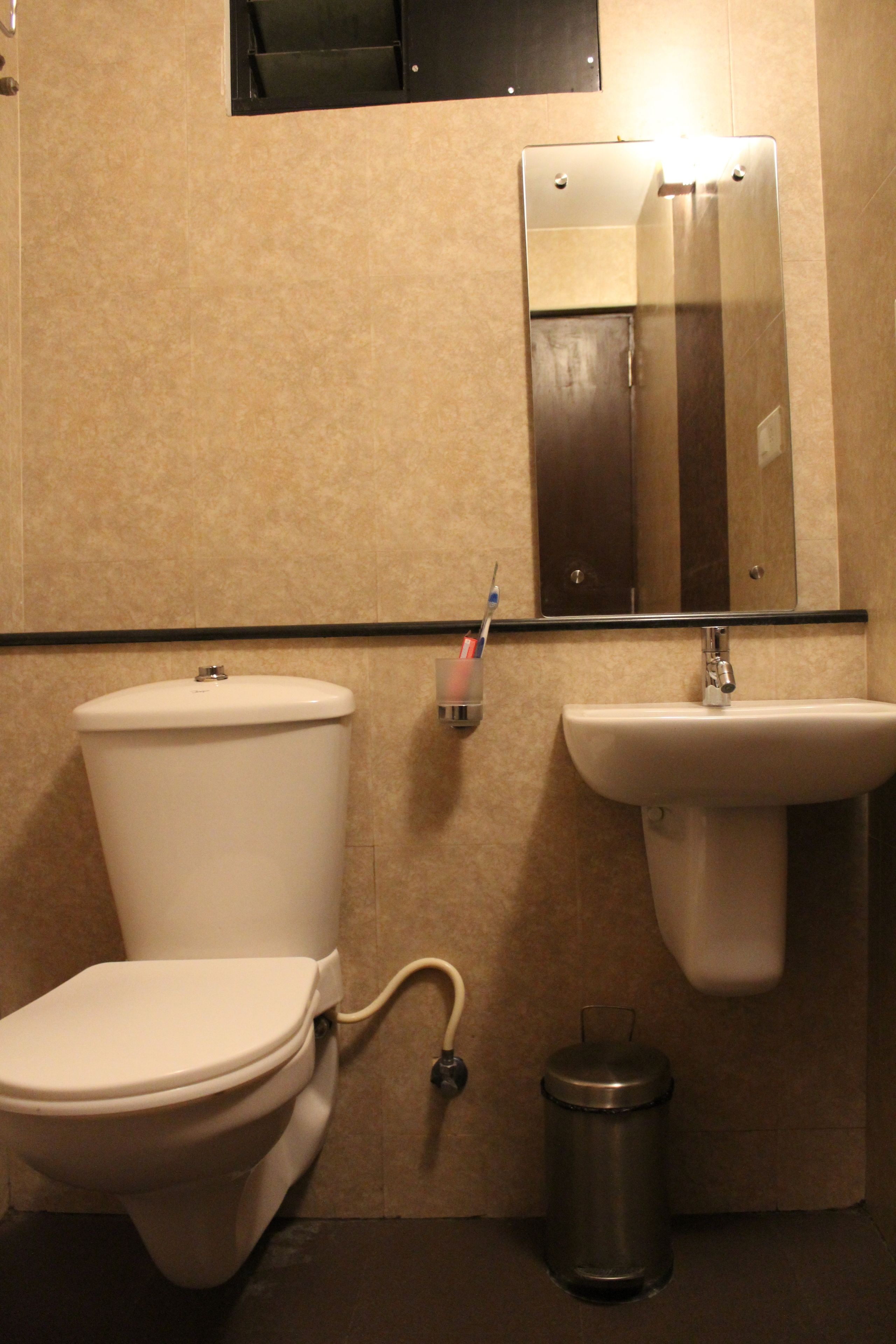 Un baño con inodoro, lavamanos y cubo de basura.