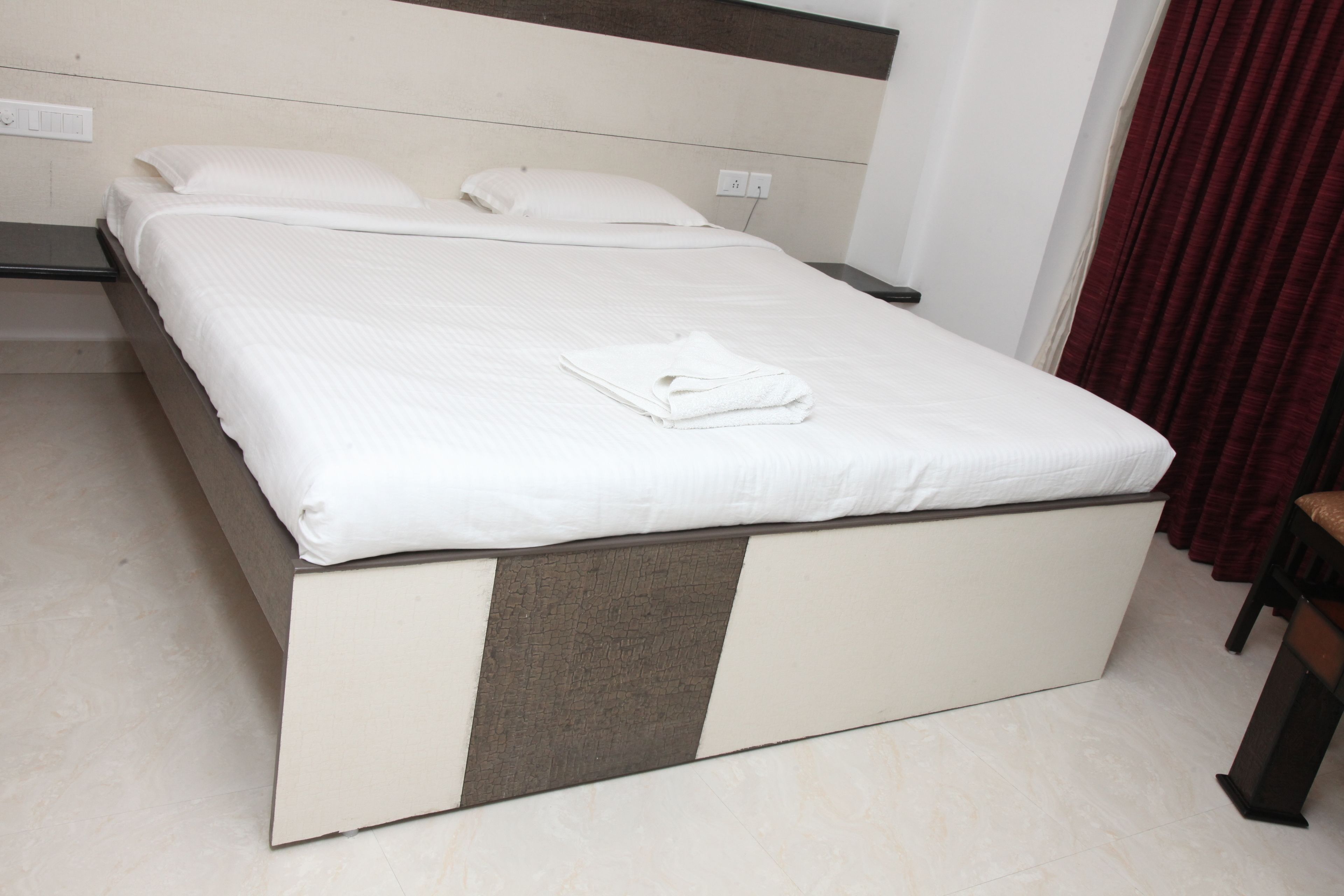 Una cama bien hecha con ropa blanca y una toalla blanca doblada encima.