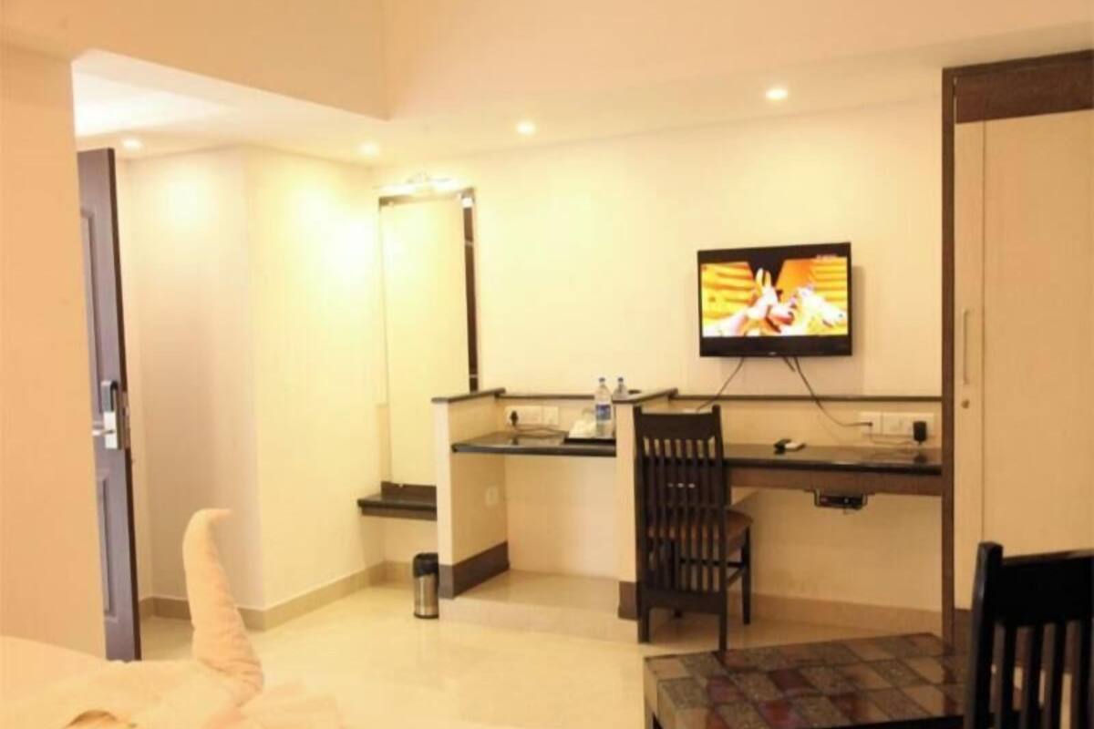 Una habitación de hotel con cama, escritorio, silla, televisor y una pequeña mesa.