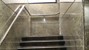 Unos escalones de mármol con barandillas de metal, que suben en un edificio moderno.