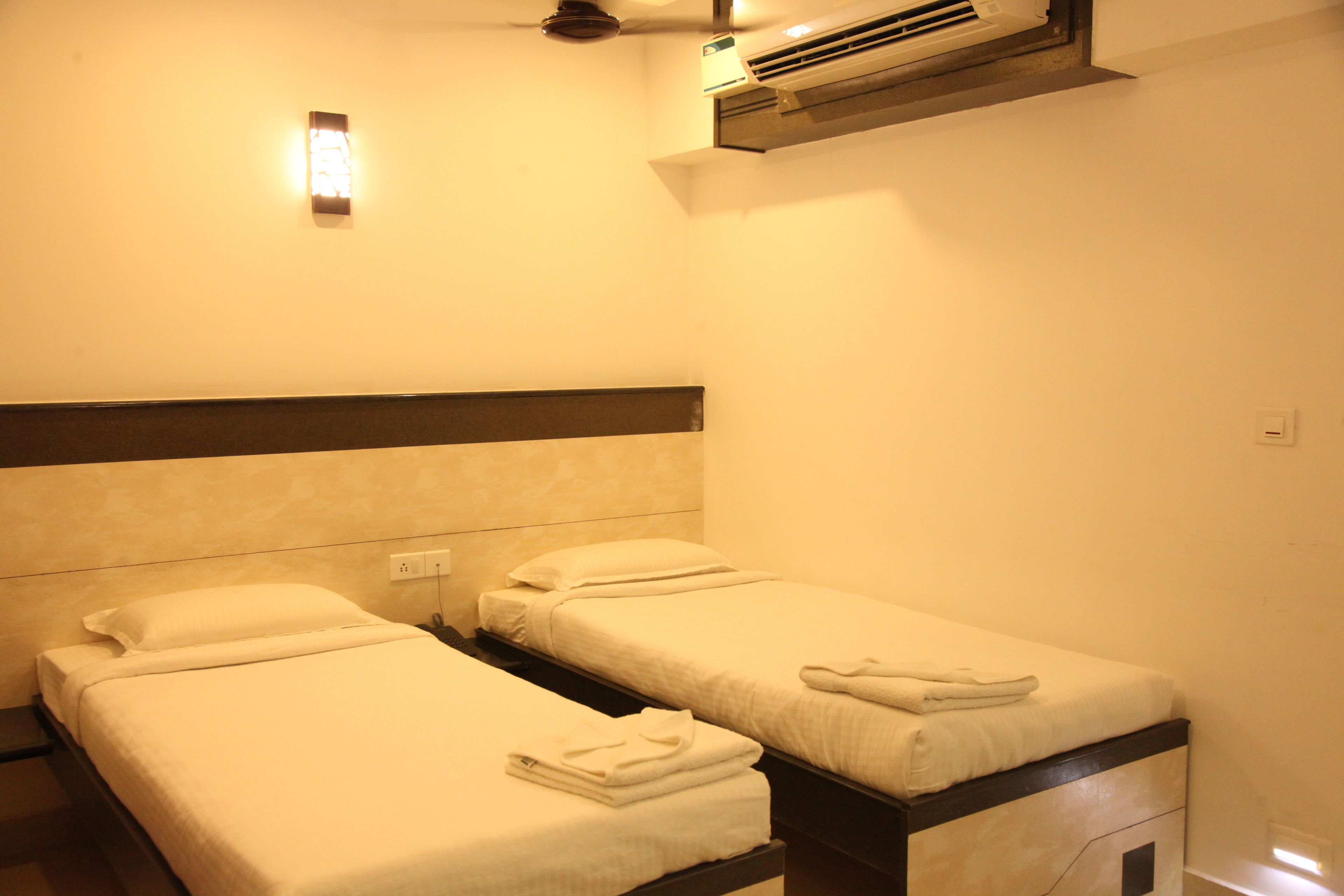 A hotel room with two single beds, each with a pillow and a folded towel.