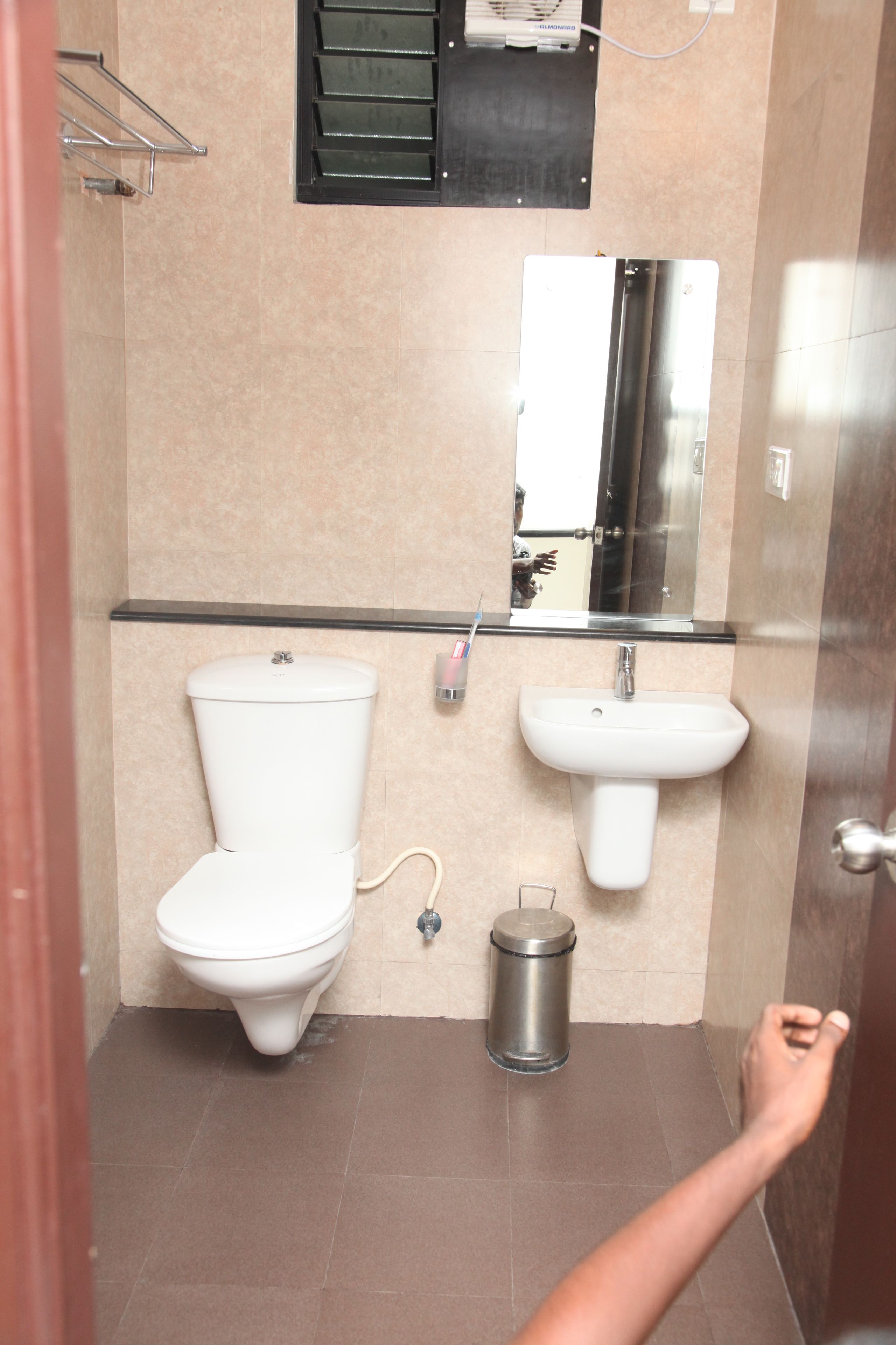 Een badkamer met toilet, wastafel en spiegel.