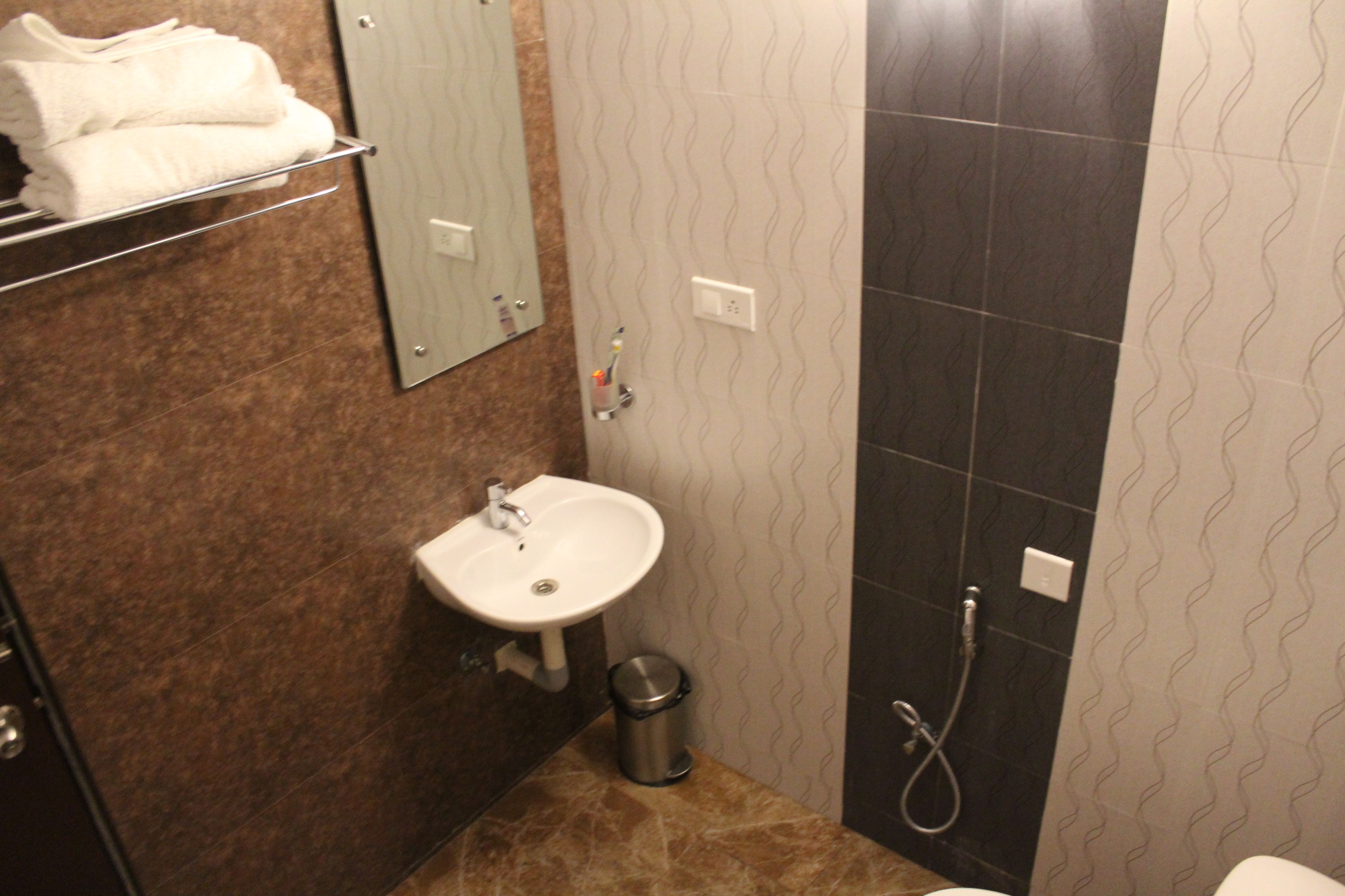 A bathroom with a sink, mirror, towel rack, and shower.