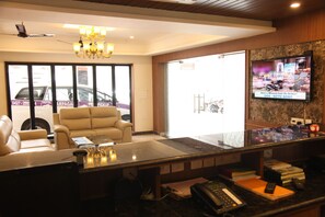 Check-in at our reception area, featuring a flat-screen TV, chandelier, and comfortable seating for guests.