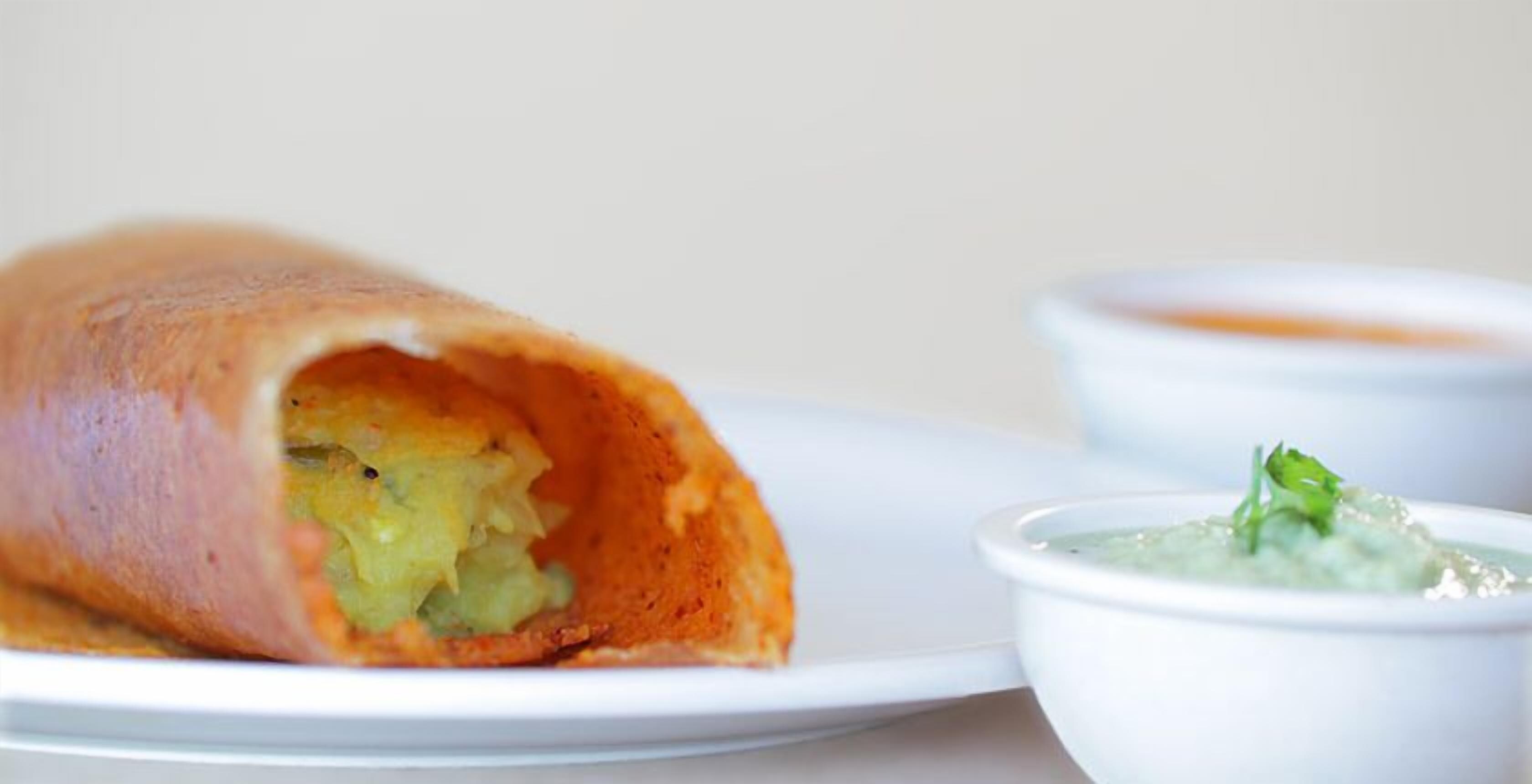 A rolled dish with a side of green sauce.