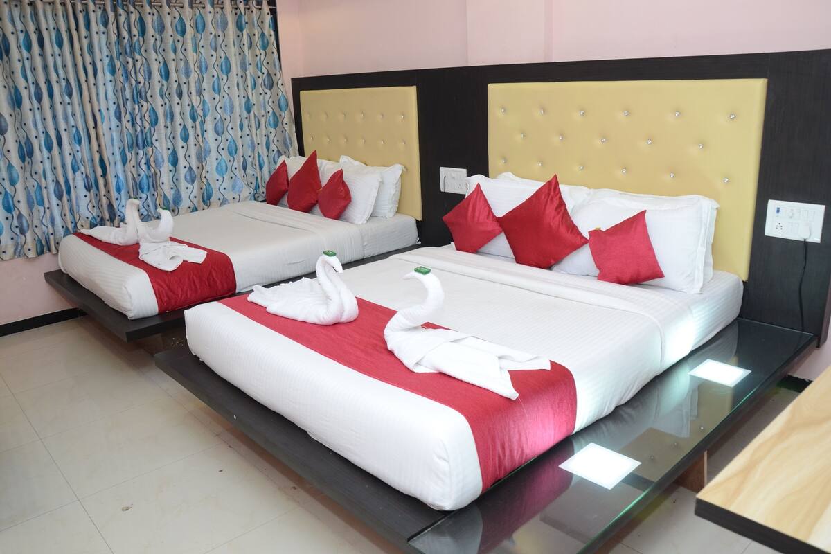 Ein Hotelzimmer mit zwei Betten, jeweils mit weißer und roter Bettwäsche sowie dekorativen Schwanenkissen.