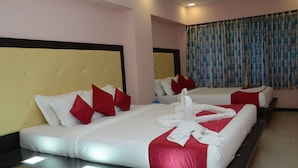 A hotel room with two beds, each with white linens and red pillows, and a red accent on the beds. - Hotel Sai Leela Grand (Mumbai)