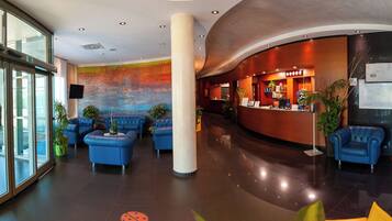 Un vestíbulo moderno con asientos azules, una recepción y un mural colorido en la pared.