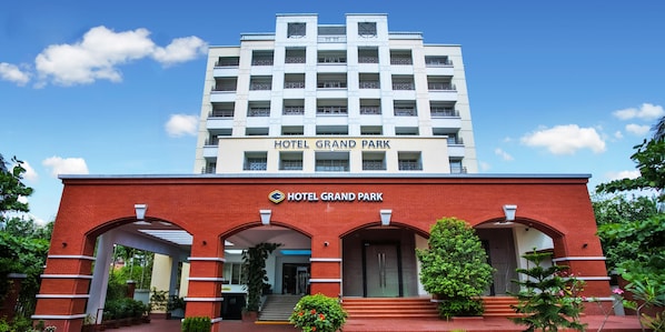 Hotelli nimeltä HOTEL GRAND PARK, jossa on moderni julkisivu, useita parvekkeita ja avoin, kirkas taivas.