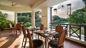 Un restaurante con sillas y mesas de mimbre, vista a un lago, y un cartel que indica zona para fumadores.