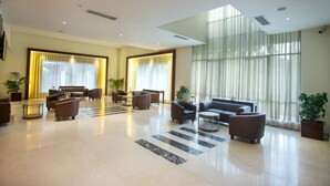 Un vestíbulo amplio con una zona de estar grande, ventanas grandes con cortinas y un diseño moderno y limpio.