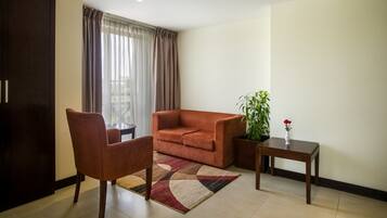 Una sala de estar con sofá, sillón y una mesita con planta y jarra.