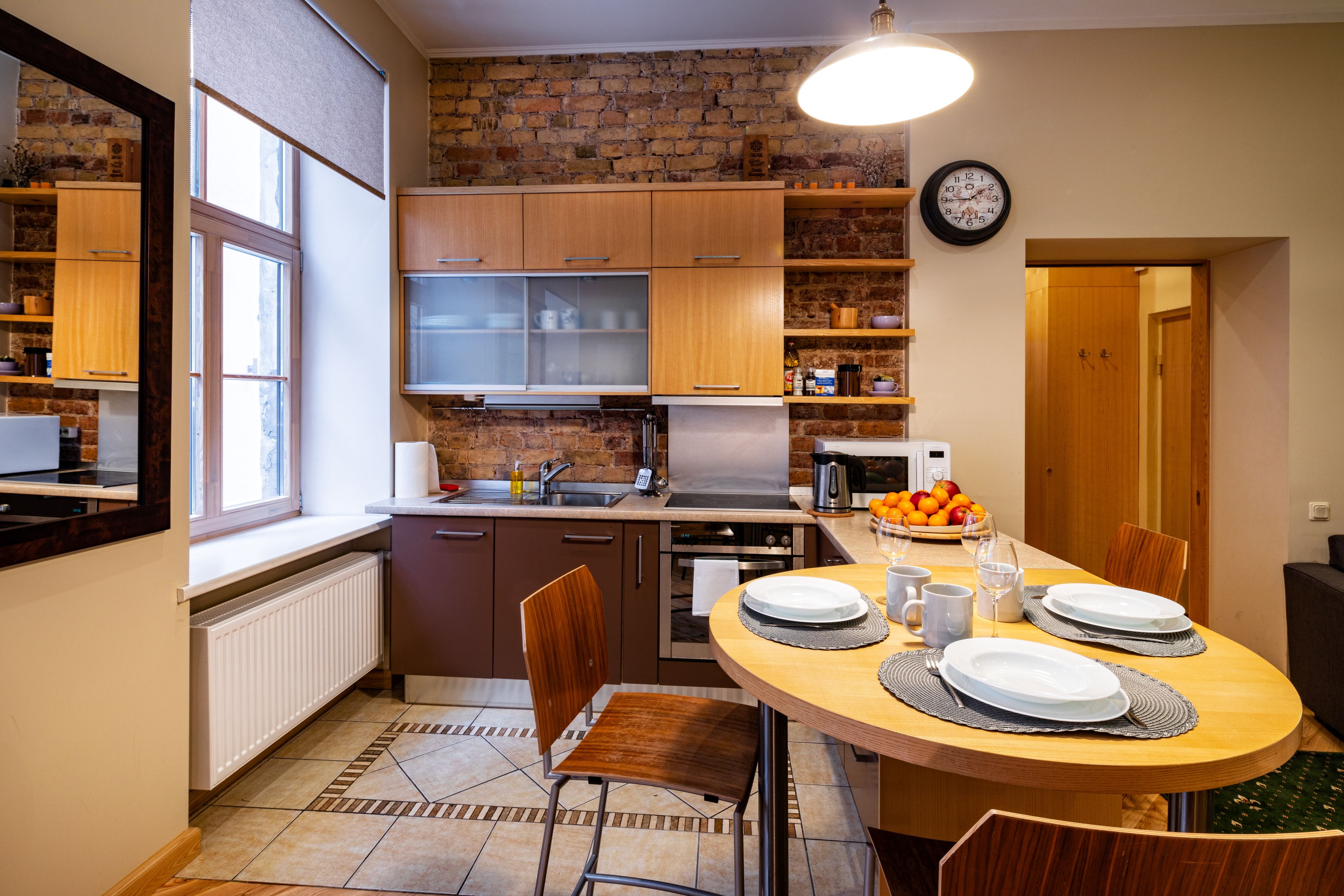 Una cocina moderna con armarios de madera, horno integrado y comedor con una mesa redonda para dos.
