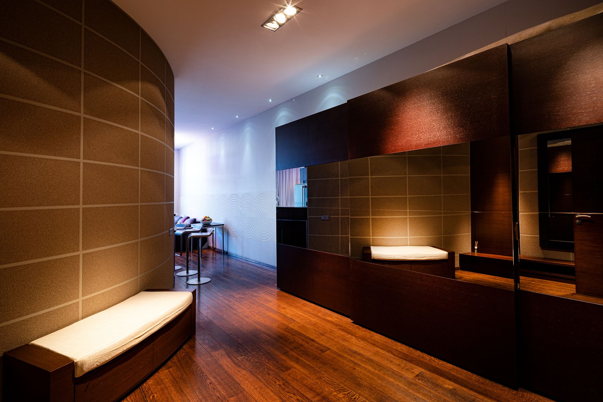 A modern bathroom with a bench, a toilet, and a mirror.