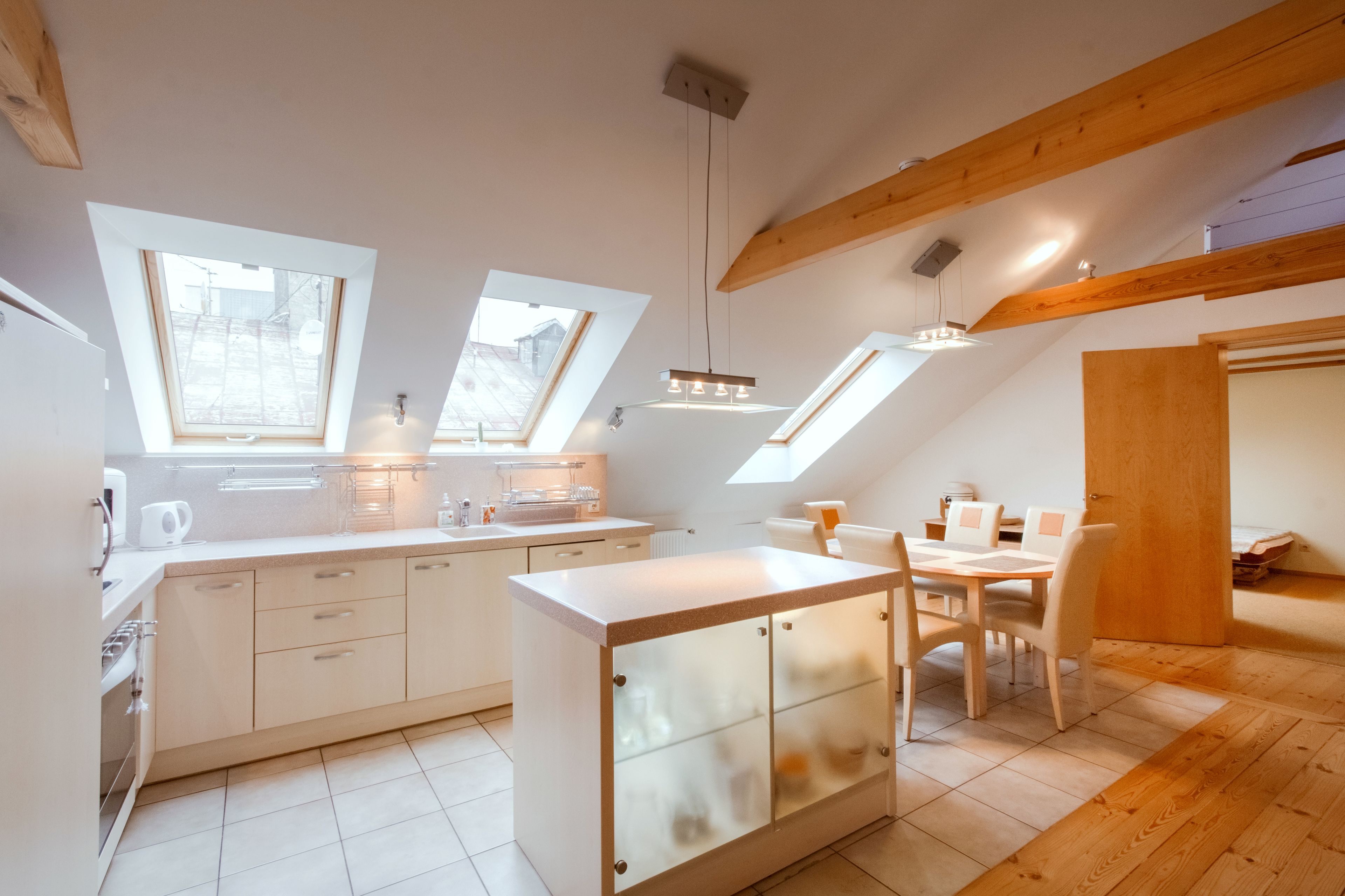 Une cuisine moderne dotée de lucarnes, d’un coin repas et de poutres en bois.