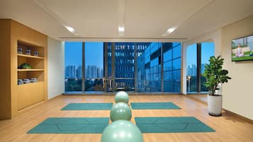 Een yogastudio met grote ramen, houten vloeren en matten.