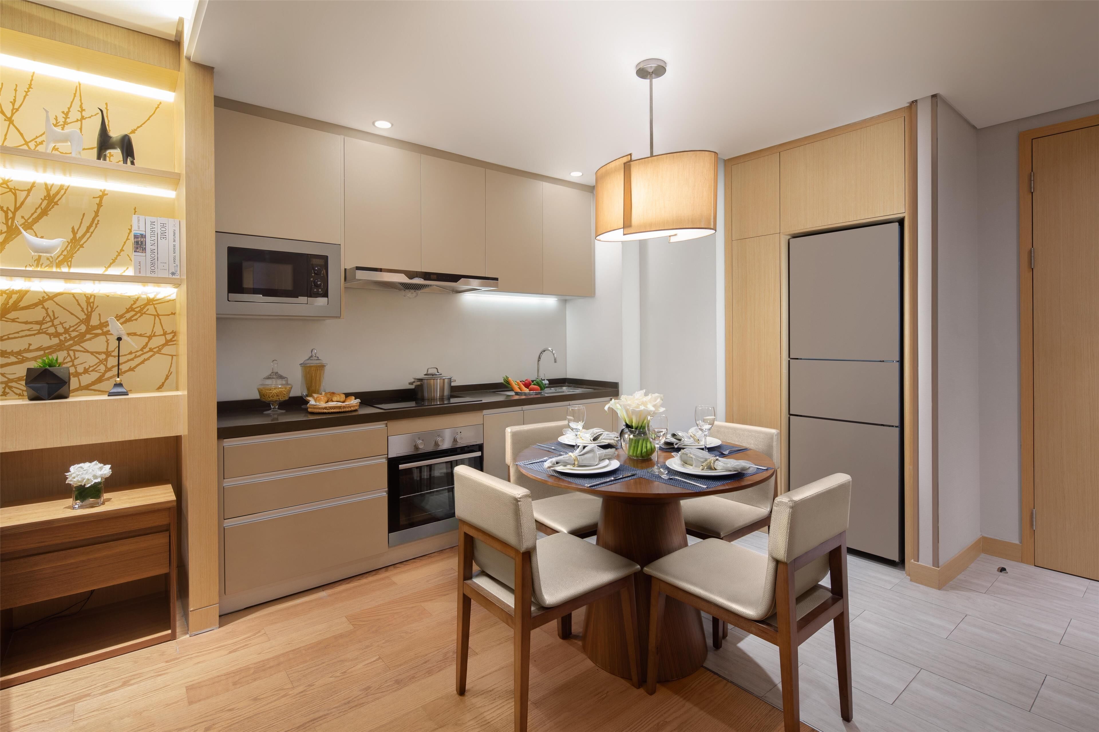 A modern kitchen with a dining area, equipped with a microwave, oven, and refrigerator.