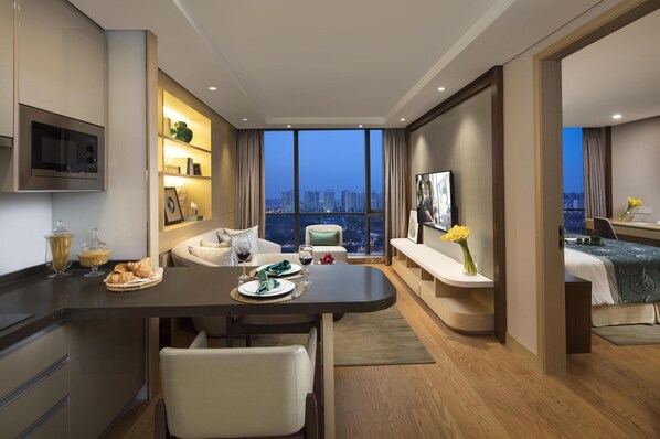 A modern hotel room with a dining area, a sofa, a bed, and a view of the cityscape. - Somerset Baitang Suzhou (Suzhou)
