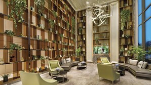 A spacious library with high wooden bookshelves filled with books and plants, a large fireplace, and comfortable seating areas. - Somerset Baitang Suzhou (Suzhou)