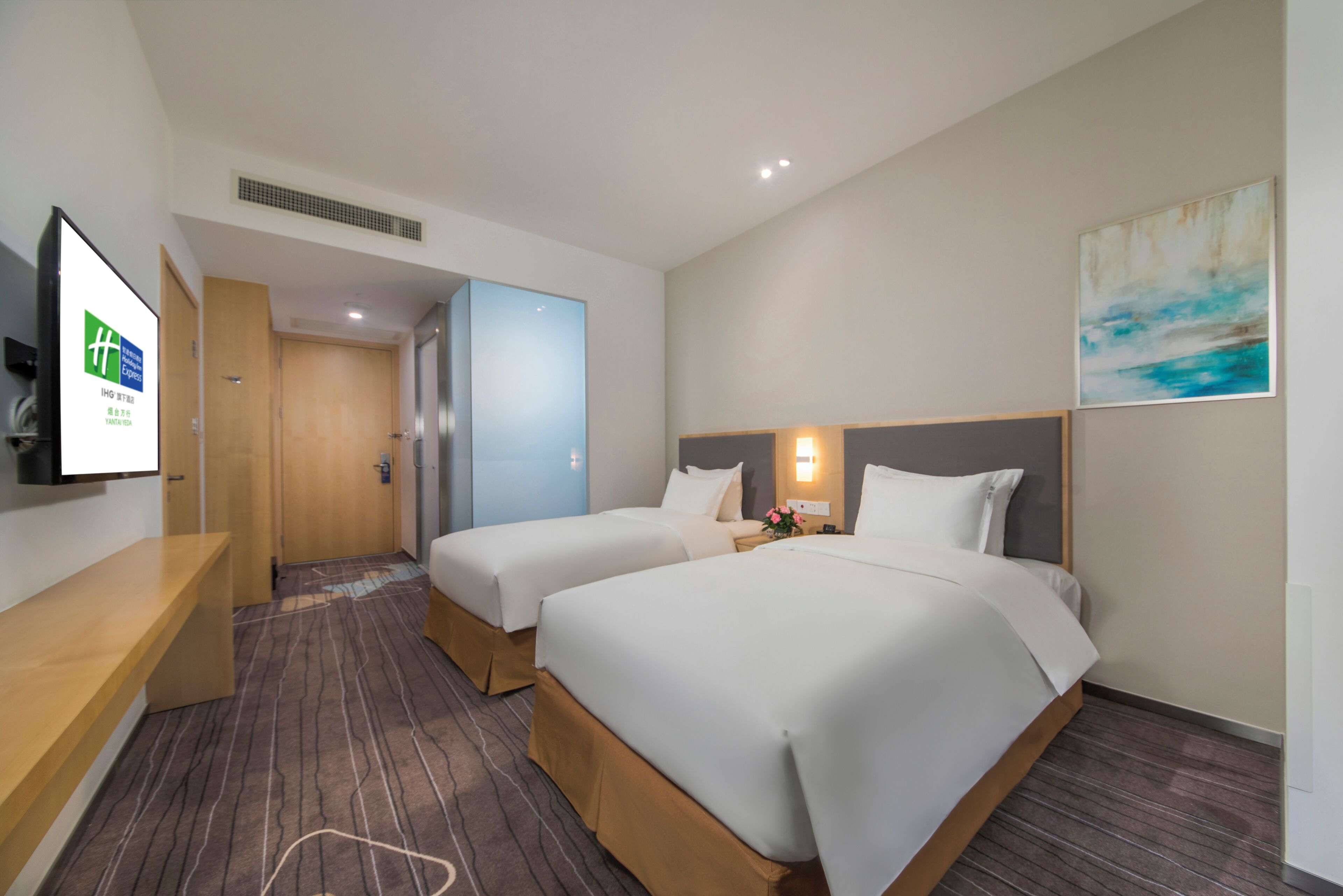 A hotel room with two beds, a TV, a desk, and a painting on the wall.