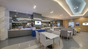 A modern hotel lobby with a central counter, seating area, and a ceiling with recessed lighting. - Holiday Inn Express Yantai Yeda by IHG (Yantai)