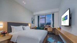A hotel room with a bed, desk, chair, and a TV on the wall. - Holiday Inn Express Yantai Yeda by IHG (Yantai)