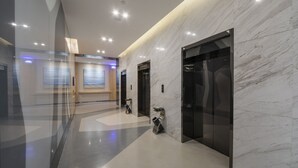 A modern hallway with marble walls, glass doors, and a polished floor. - Holiday Inn Express Yantai Yeda by IHG (Yantai)
