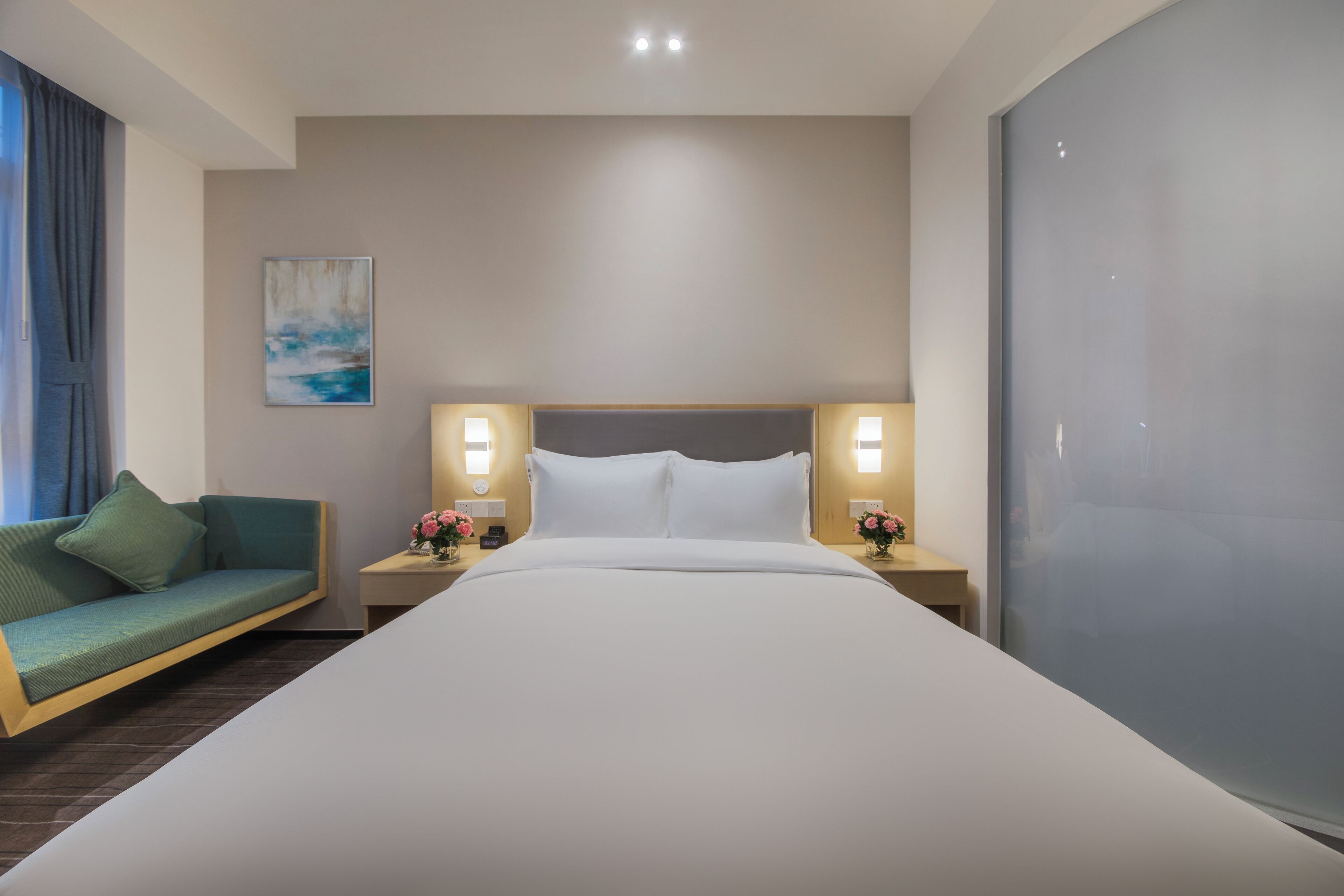 Una habitación de hotel con una cama grande, dos mesitas de noche con lámparas, un sofá y un cuadro en la pared.