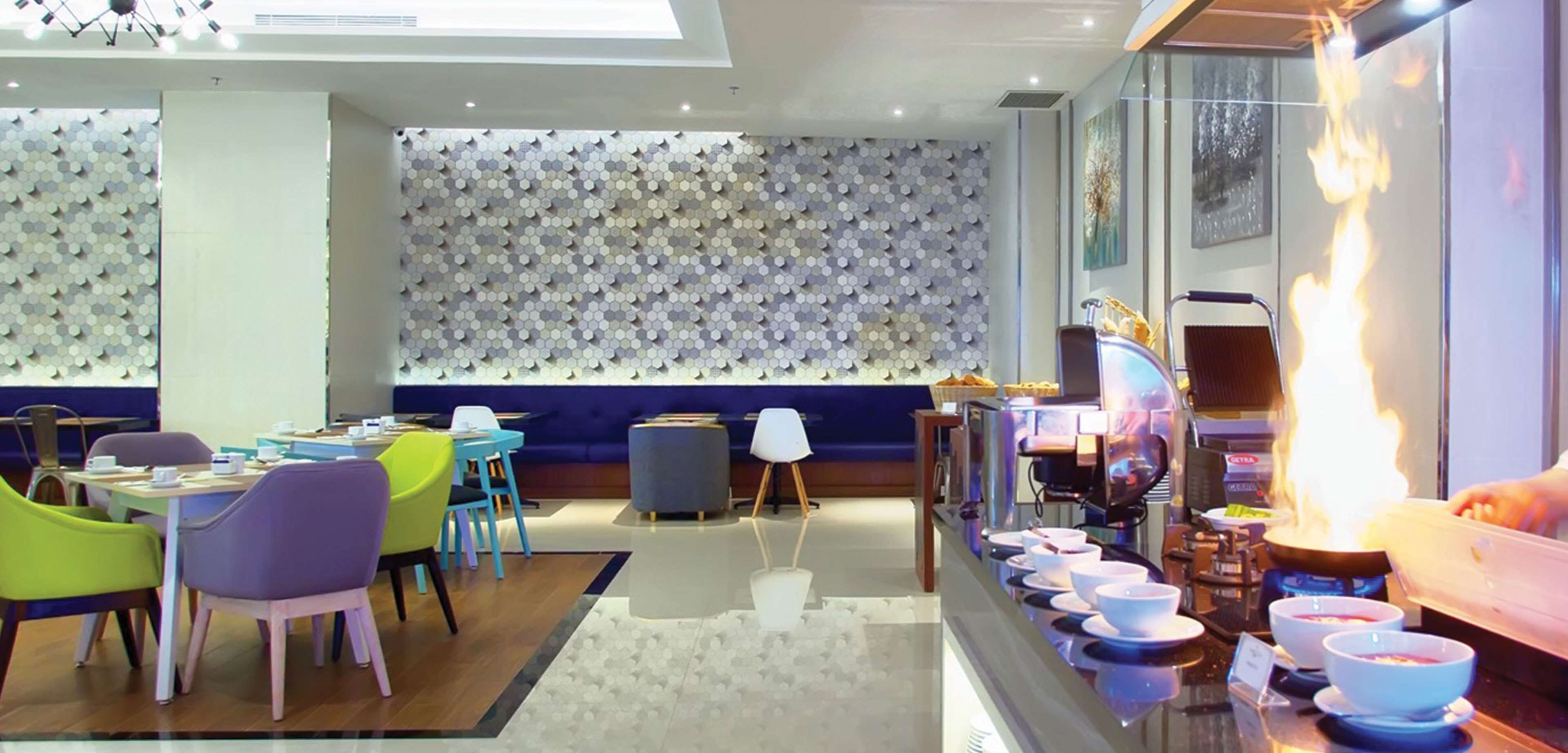 A modern dining area with a long counter, colorful chairs, and a central seating area.