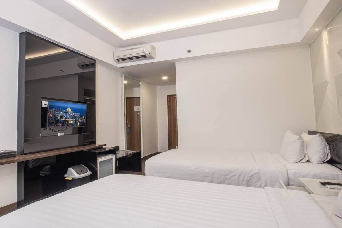 Una habitación de hotel con dos camas, televisión y minibar.