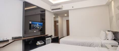 A hotel room with two beds, a TV, and a minibar.