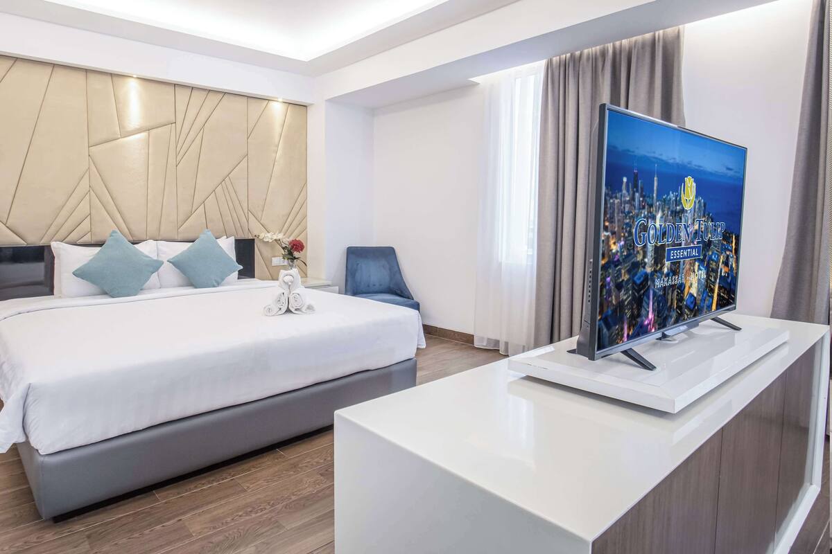 Una habitación de hotel moderna con una cama grande, televisión de pantalla plana y vistas a la ciudad.