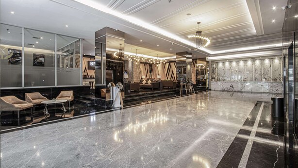 A modern lobby with a marble floor, seating area, and a reception desk. - Golden Tulip Essential Makassar (Makassar)