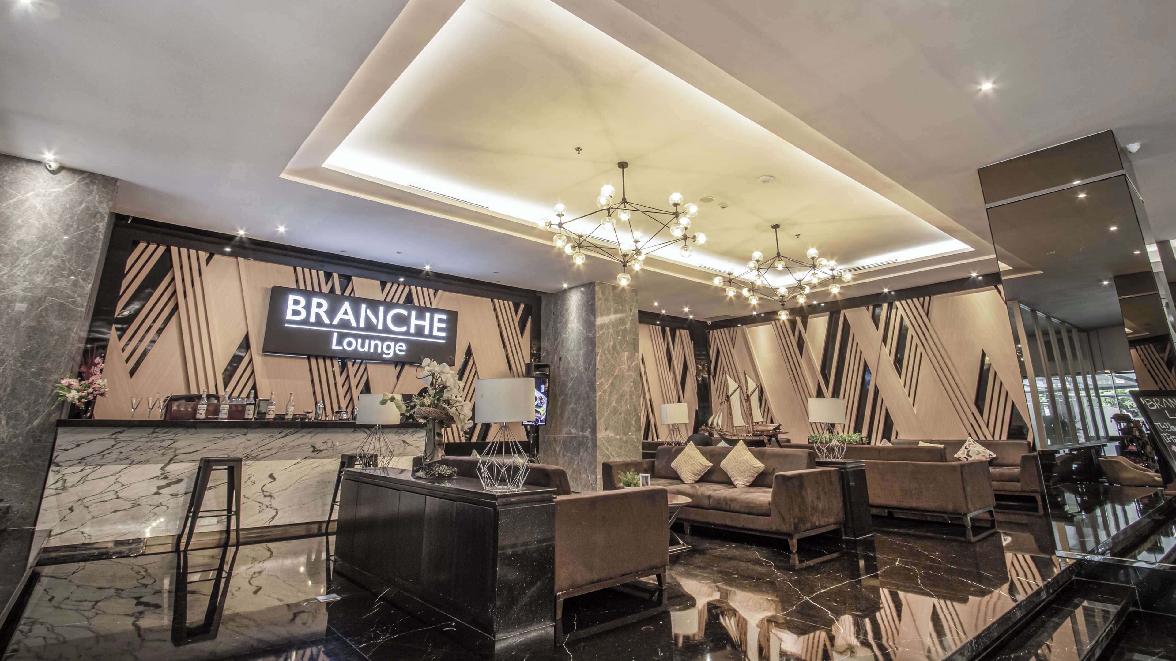 Een moderne lounge met een marmeren receptiebalie, comfortabele zitplaatsen en een kroonluchter.