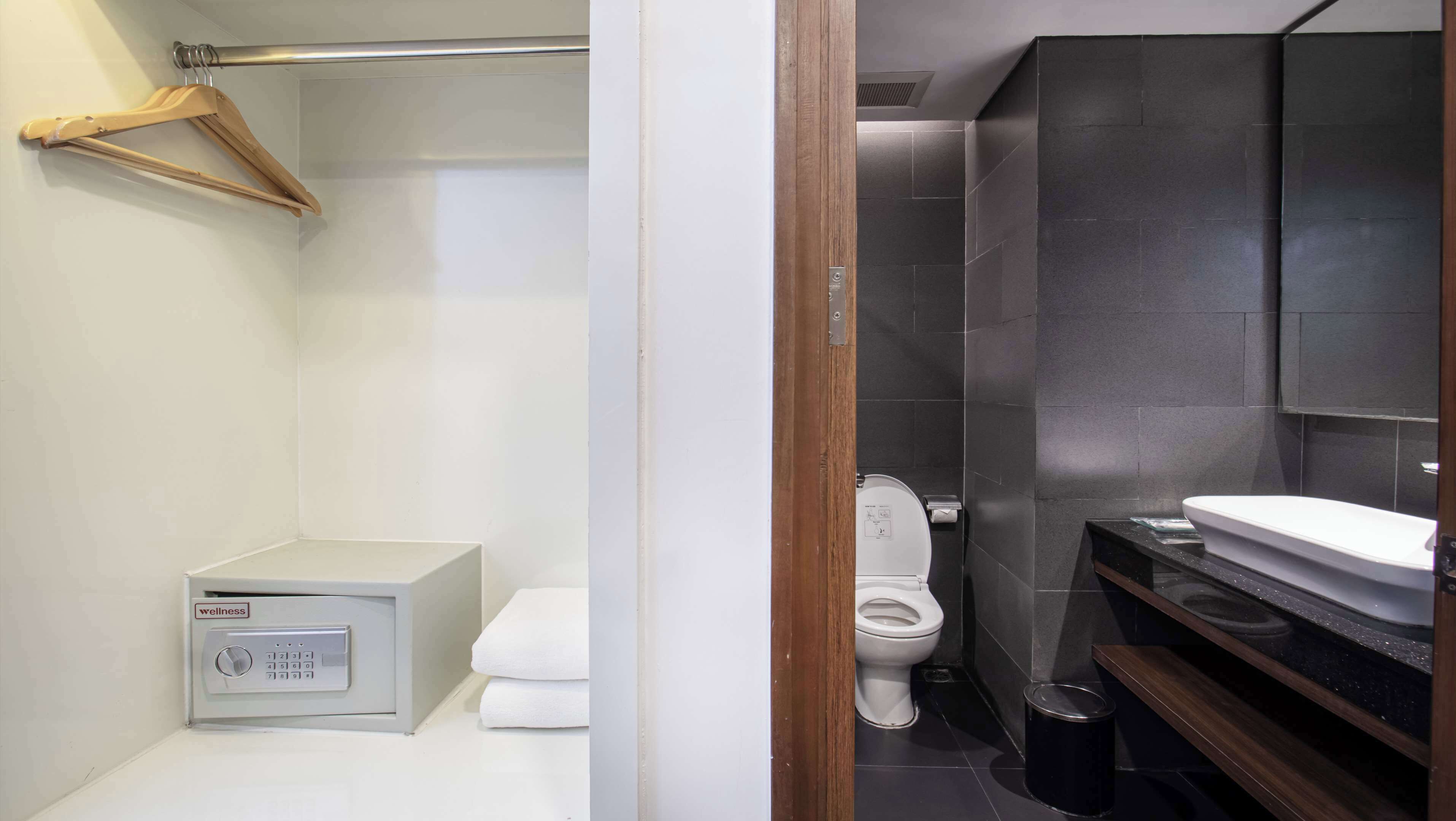 Une salle de bain moderne avec des toilettes blanches, un espace douche et un meuble-lavabo avec un miroir.