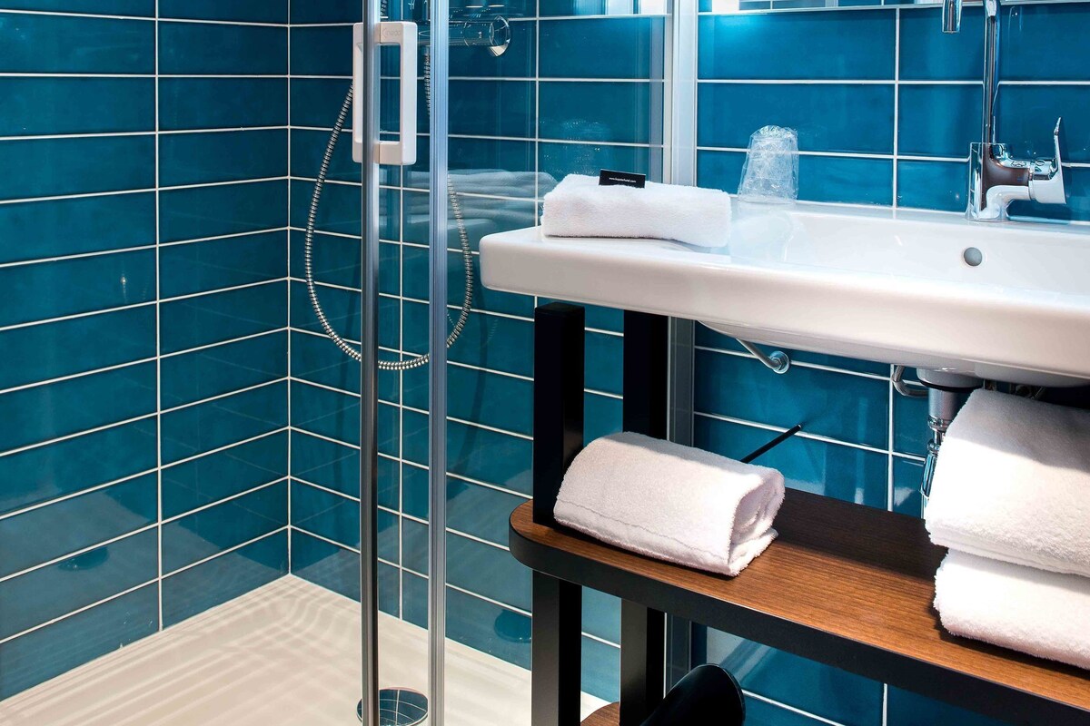 A modern bathroom with a glass shower enclosure, a white sink, and a mirror above it.