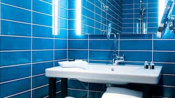 A modern bathroom with blue tiles, a white sink, and a mirror.