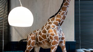 A giraffe statue in a room with a blue armchair, a yellow armchair, and a wooden coffee table. - Kopster Hotel Lyon Groupama Stadium (Decines-Charpieu)