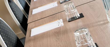 Una mesa de conferencias con sillas, documentos y cristalería.