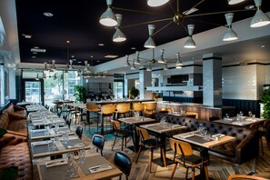 Un restaurant doté de plusieurs espaces de restauration, notamment des banquettes et des tables, ainsi qu’un bar.