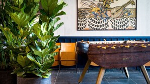 A foosball table, a large potted plant, and a painting on the wall. - Kopster Hotel Lyon Groupama Stadium (Decines-Charpieu)