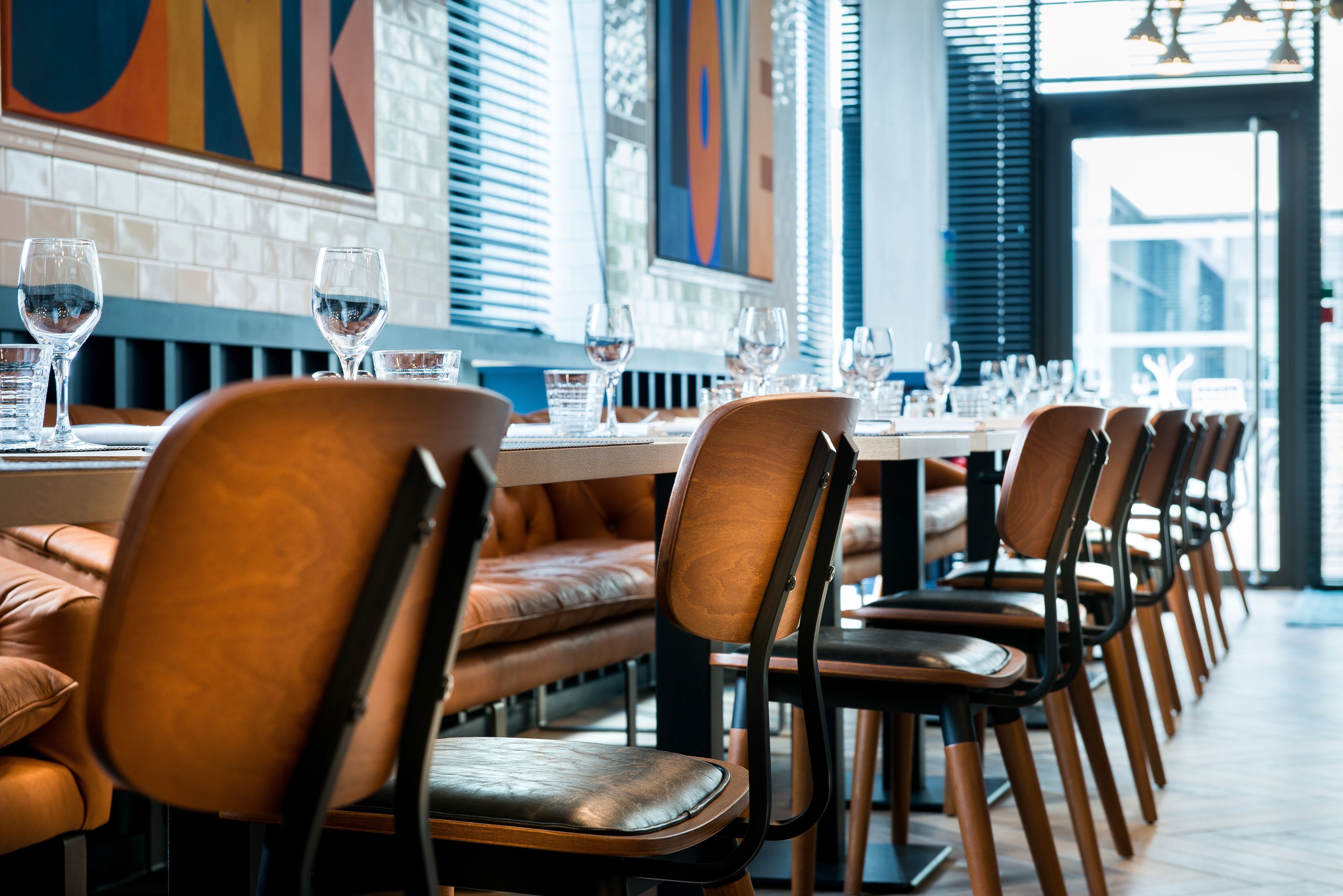 Een restaurant met lederen zittingen en een lange tafel gedekt met wijnglazen en waterglazen.